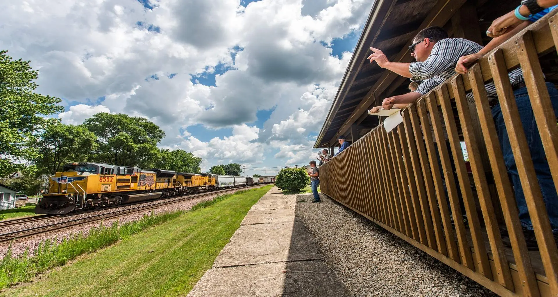 Gente viendo pasar un tren en un parque ferroviario