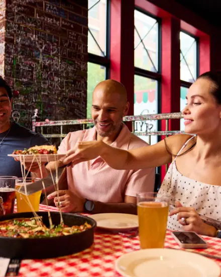 Unos amigos compartiendo pizza y bebidas en un restaurante.